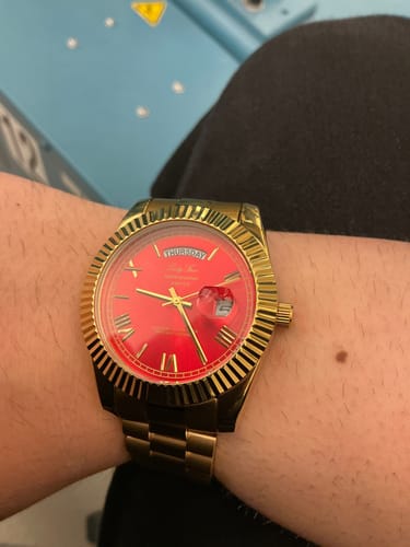 Customer wearing their gold Lucky Fours® Santos watch with a red face.
