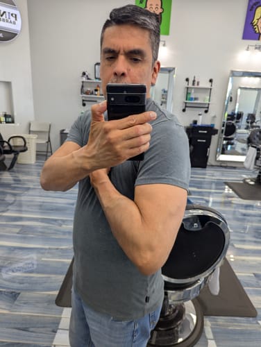 Reviewer flexing their arm in a mirror selfie, showing results from taking the TITAN supplement.