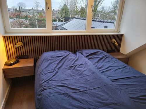 Recensent toont twee houten, zwevende Fermo nachtkastjes, gemonteerd naast een bed.