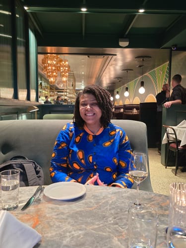 Customer celebrating her birthday wearing the blue Damini African Print Polo Shirt at a restaurant.