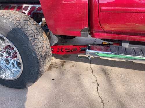 Close-up of a customer's Traction Bar Kit, painted red to match their truck and installed under the vehicle.