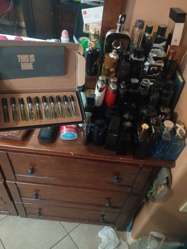 Il cliente mostra il Set campioni orientali e legnose aperto su un comò, accanto ad una vasta collezione di profumi.