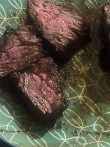 Close-up of a reviewer's sliced Outside Skirt Steak with a seared crust and pink center.