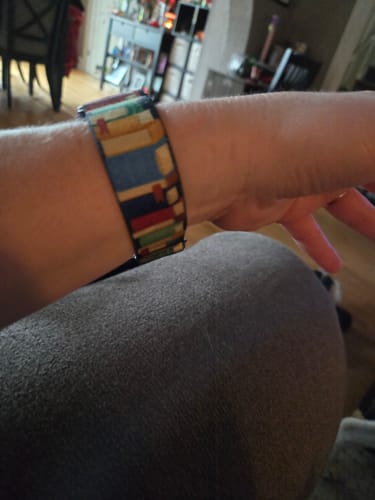 Customer's wrist wearing the Start A New Chapter Watch Band, which features a colorful book pattern.
