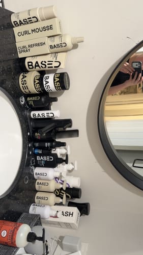 Reviewer's large collection of BASED brand products, including the Conditioner, arranged on a bathroom counter.
