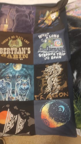 Close-up of a customer's Project Repat T-Shirt Quilt, showing squares with wolves, a dragon, and other memorable graphics.