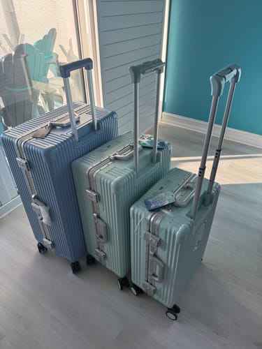 Customer's three hardshell suitcases in blue and mint colors, lined up by size with handles extended.