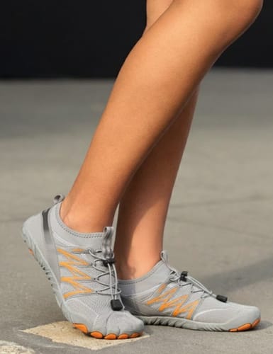 A reviewer wearing the grey BareEase shoes, showing the flexible sole and orange accents.