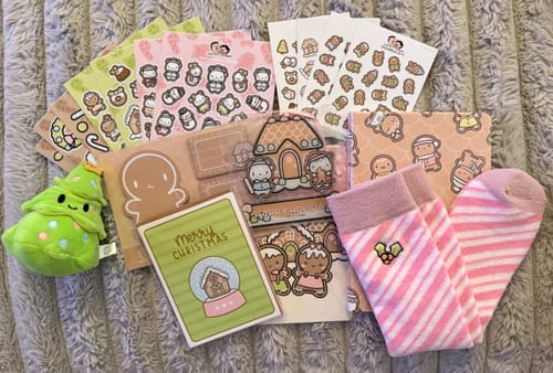Customer's flat lay of the adorable contents from the Gingerbread Holiday Advent Calendar, including stickers, socks, and a plush toy.