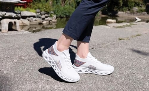 Reviewer standing outdoors in white Ortho Step shoes, showing the unique cutout sole design.