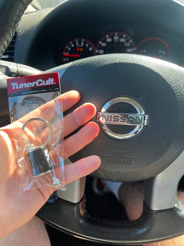 Customer holding the Functional Shifter Keychain in its original packaging inside a car.