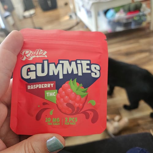 Customer holding a red pouch of ROLLZ Raspberry THC Gummies, showing 10 MG and 3 pieces per pack.