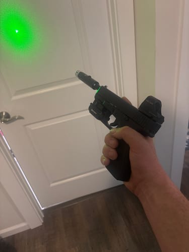 Customer using the Site Right™ 2.0 - Boresighter in a handgun, projecting a green laser onto a door.