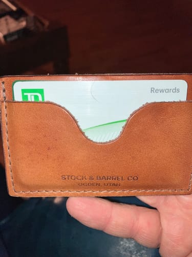 Customer holding the No.54 'Buck Brown' leather wallet with a card visible in the front pocket.