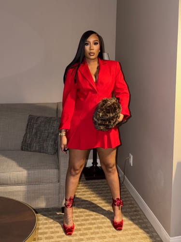 Customer standing in a red Suiting Blazer Mini Dress, providing a full view of the dress and its pleated hem.