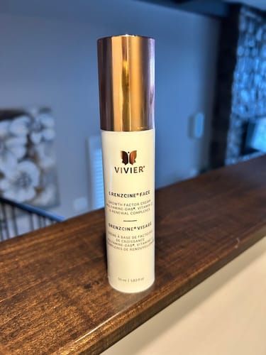 Reviewer's Vivier GrenzCine Face cream bottle with a shiny cap sitting on a wooden ledge.