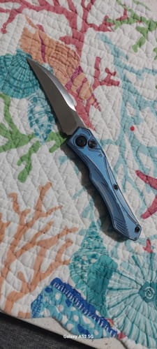 Customer's Hendrix Hell Hawk switchblade with a blue anodized handle, shown open on a patterned quilt.
