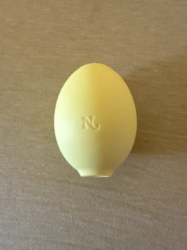 Customer's yellow Lem Clitoral Massager resting on a neutral textured surface.