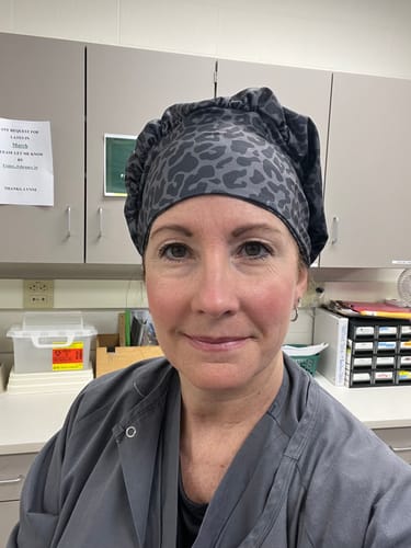 Reviewer in a clinical setting wearing the slouchy DuoStyle Scrub Hat in an Onyx Leopard print.