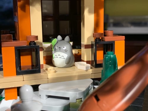 Reviewer's Mini Totoro Figure holding a leaf, placed outside a tearoom in their Lego Japanese garden.