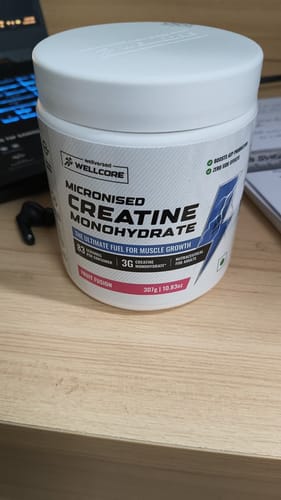 Customer's white tub of Wellcore Micronised Creatine Monohydrate in Fruit Fusion flavor sitting on a desk.