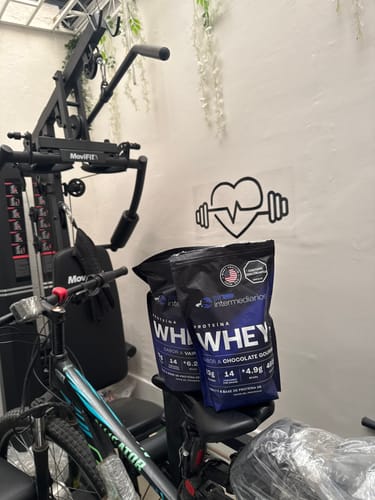 Cliente con sus bolsas de Proteína Whey de Vainilla y Chocolate en un gimnasio casero.