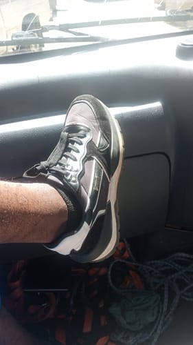 Close-up of a reviewer wearing the black and grey Urbanart Athene sneaker on their foot inside a vehicle.