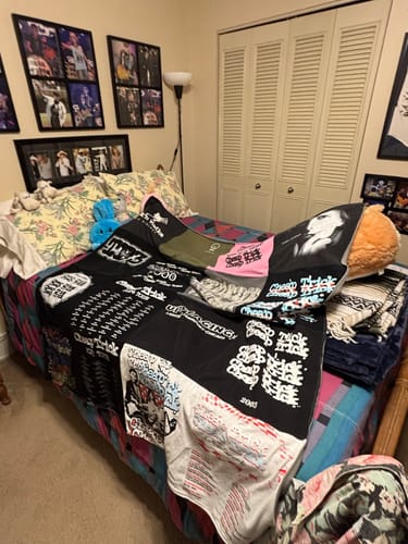 Customer's Project Repat T-Shirt Quilt made from various dark t-shirts, laid out on a bed in a bedroom.