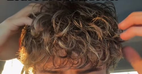 Customer running their hands through their curly, styled hair after using the Pomade.