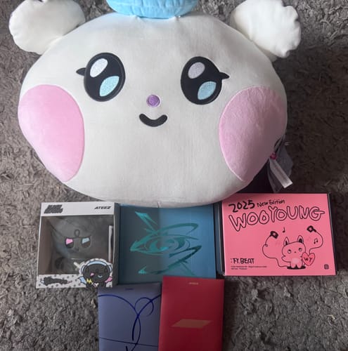 Reviewer's items from their K-POP RANDOM BOX, including a large white plushie, several albums, and a boxed toy.