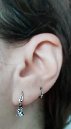 Close-up of a customer's ear wearing the silver Gaia Huggies, showing the interwoven design and sparkle accent.