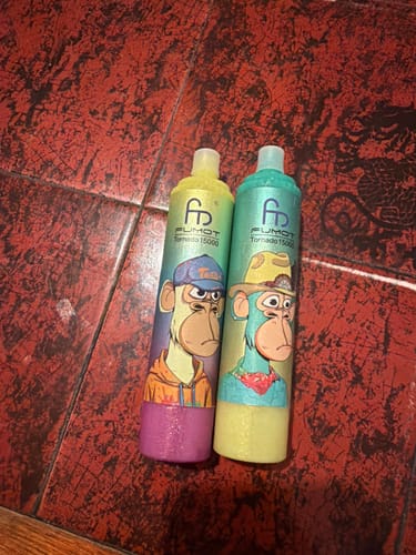 Customer's two colorful RandM Tornado 15000 vapes with cartoon graphics lying on a red tiled floor.