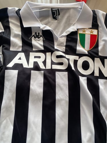 Recensore mostra un primo piano della maglia storica della Juventus, con colletto bianco, sponsor Ariston e stemma.