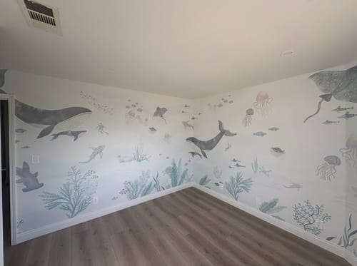 Customer's room with the Under the Sea Wallpaper on two walls, featuring charming watercolor-style whales, fish, and plants.