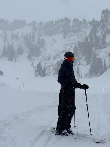 Customer wearing the baggy snow pants and full ski gear while standing in a snowy, mountainous area.