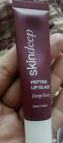 Customer holding the Skindeep Peptide Lip Glaze in the shade Deep Berry.