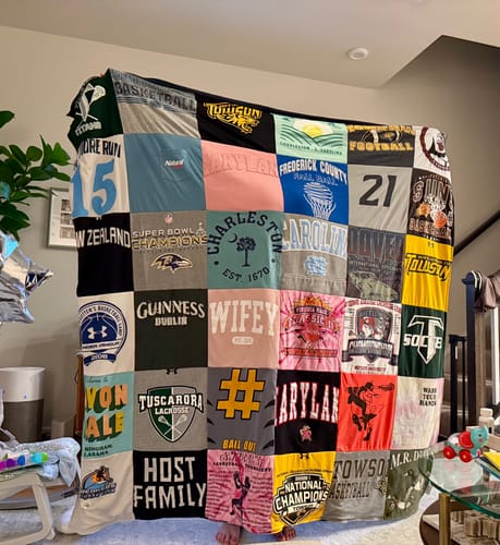 Reviewer displaying their large Project Repat T Shirt Quilt, made from a colorful collection of t-shirts.