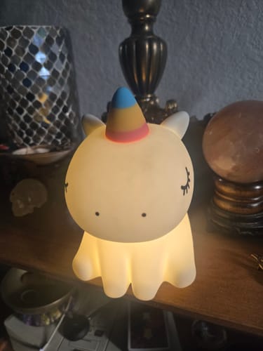 Customer's Unicorn Night Light emitting a warm glow on a wooden shelf.
