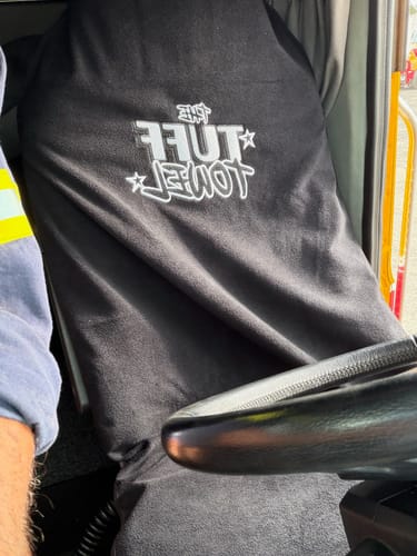 Customer's black Waterproof Car Towel Seat Cover shown fitted on a truck's driver seat, with the logo visible.