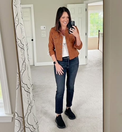 Reviewer taking a mirror selfie wearing black Ortho Slip shoes with dark jeans and a brown jacket.