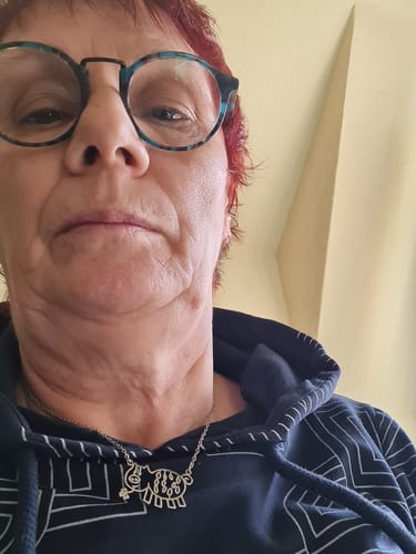 Kundin trägt ihre personalisierte Halskette mit einem silberfarbenen Anhänger, der wie eine Kinderzeichnung eines Tieres geformt ist.