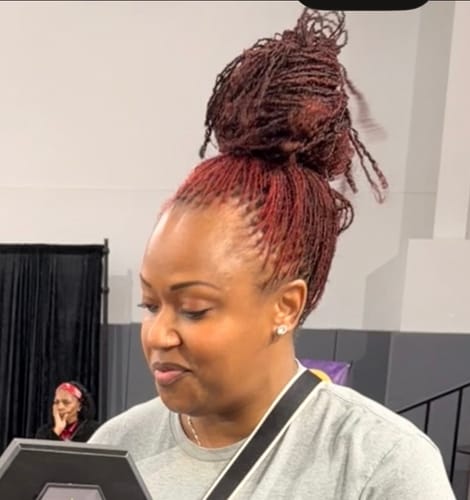 Customer with vibrant, red-colored micro-locs styled in a high bun after using the Instant Dye Shampoo.