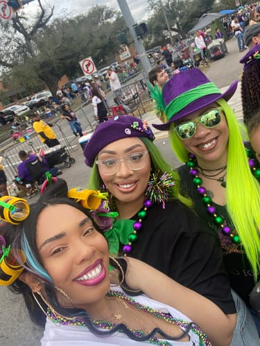 Three reviewers at an outdoor parade, one wearing the long, neon green Sensationnel Empress wig.