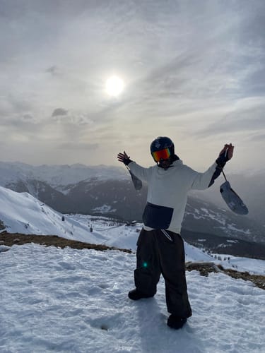 Reviewer wearing the black baggy waterproof snow pants on a snowy mountain.