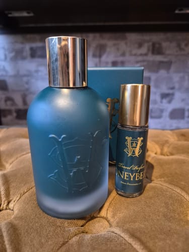 A customer's full-size frosted bottle of Honeyberry fragrance next to the travel-size rollerball.