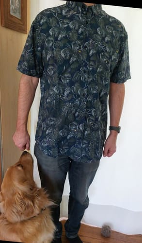 Reviewer wearing the Jurassic Park 'Clever Girl' shirt, showing its relaxed fit and dark, dense jungle pattern indoors.