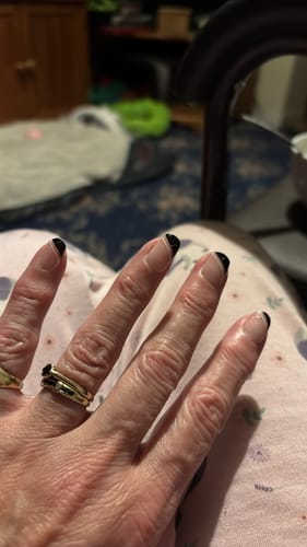 Customer's hand showing a professional French manicure with black tips, applied using the Holy Gels Starter Kit.