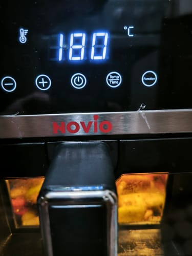 Recenzent arată un prim-plan al panoului digital al friteuzei Novio StonePro, setat la 180°C în timpul gătirii.