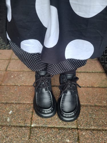 Customer's top-down view of the black leather platform ankle boots, styled with a polka-dot skirt and leggings.