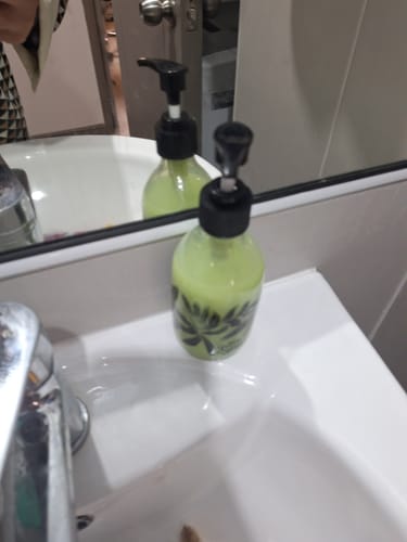 Un cliente muestra el dispensador floral con líquido verde en el lavamanos de su baño.